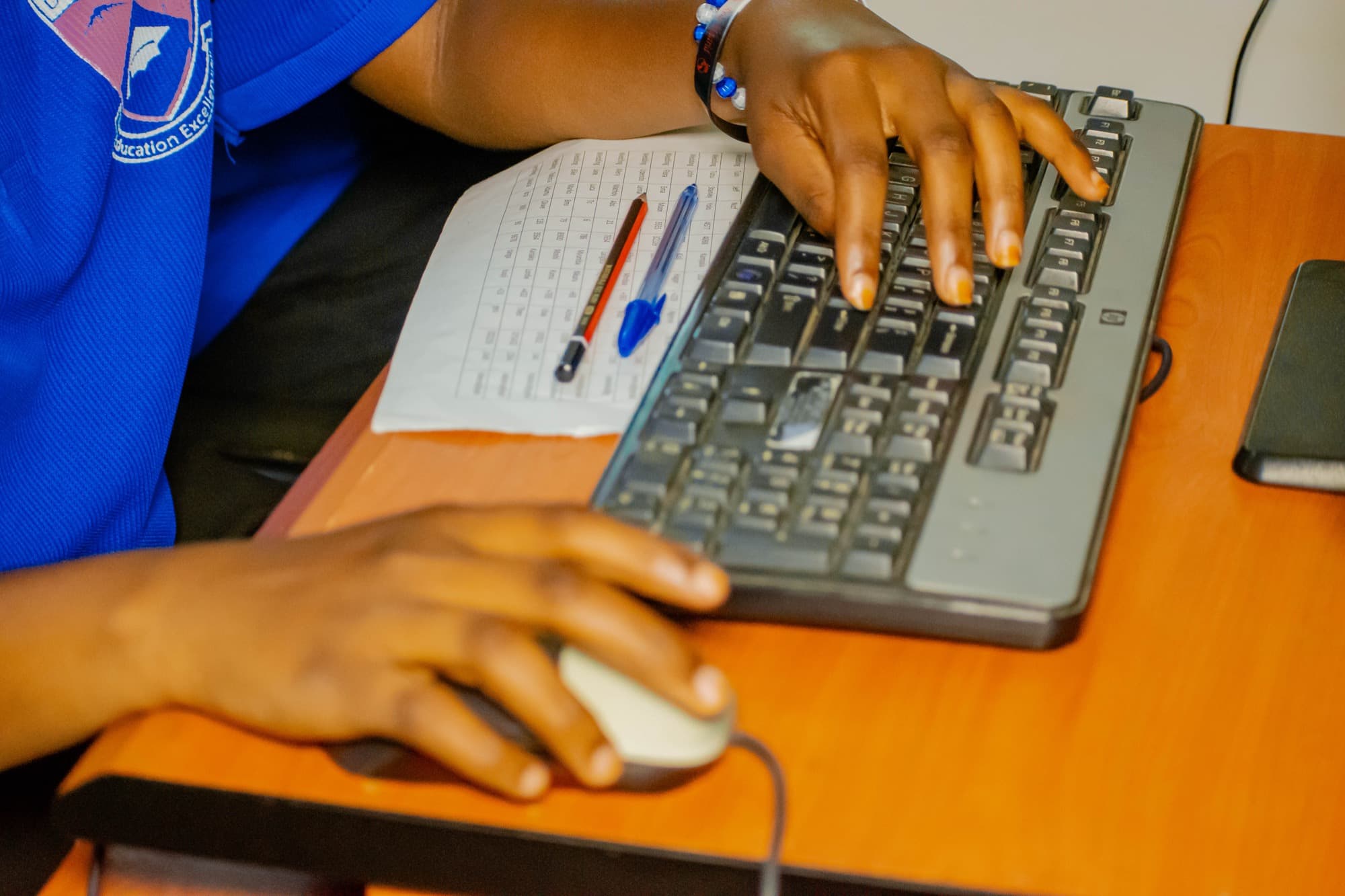 A student's hands typing on a computer keyboard during a practical session